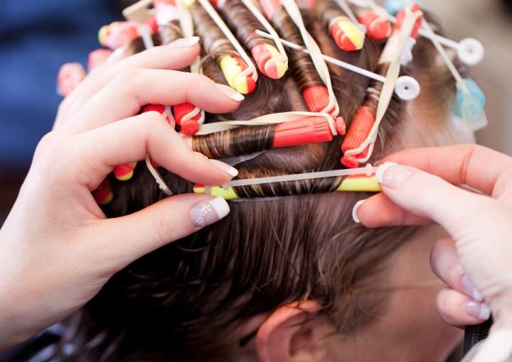 Hairdresser wrapping hair in perm rods