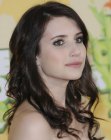 Brunette Emma Roberts wearing her hair with curls and a short side part