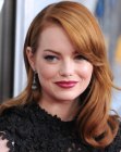 Emma Stone with her hair cut in face framing layers and styled with an off-center part