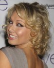 Kym Johnson wearing a medium length hairstyle with large curls