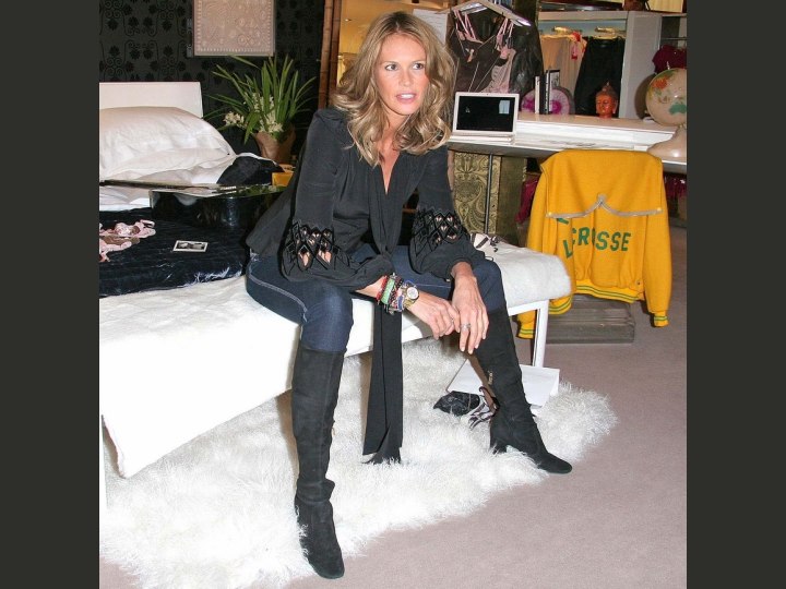 Elle MacPherson wearing a silk blouse, jeans and boots