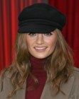 Stana Katic with long curly hair and wearing a hat