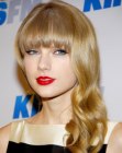 Taylor Swift's long hairstyle with heavy bangs and loose curls