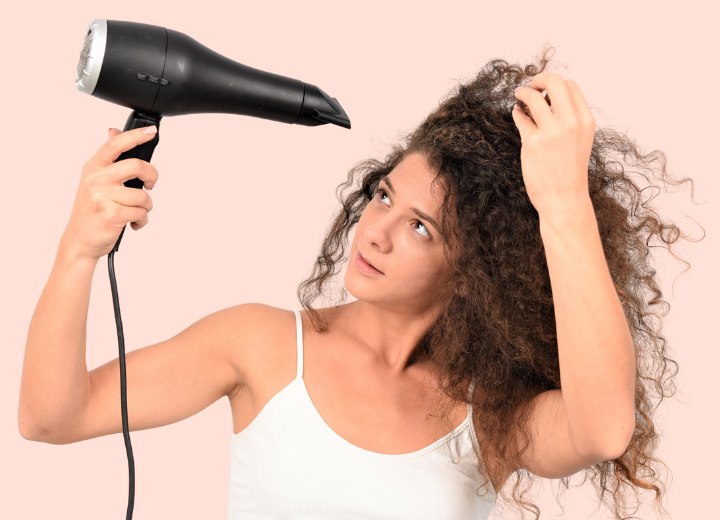 Girl blow drying long hair with tight curls