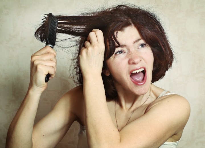 Woman trying to brush hair with knots