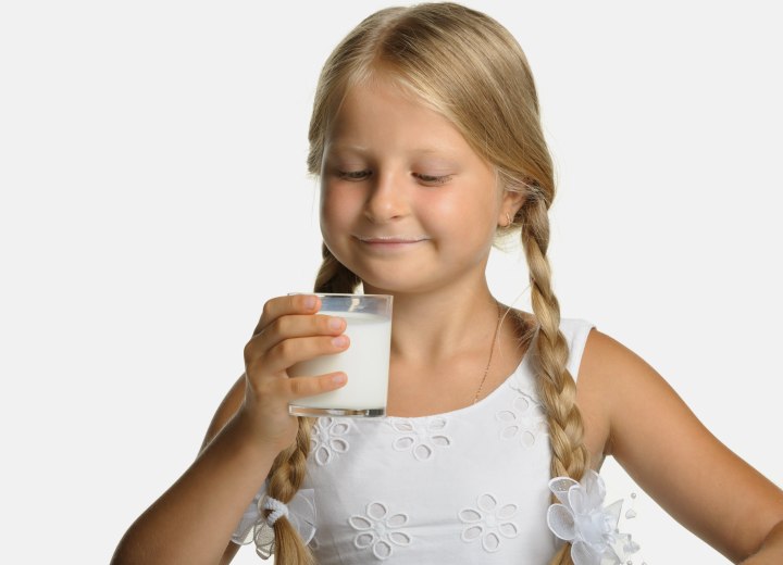 Young girl with pigtails who is drinking milk