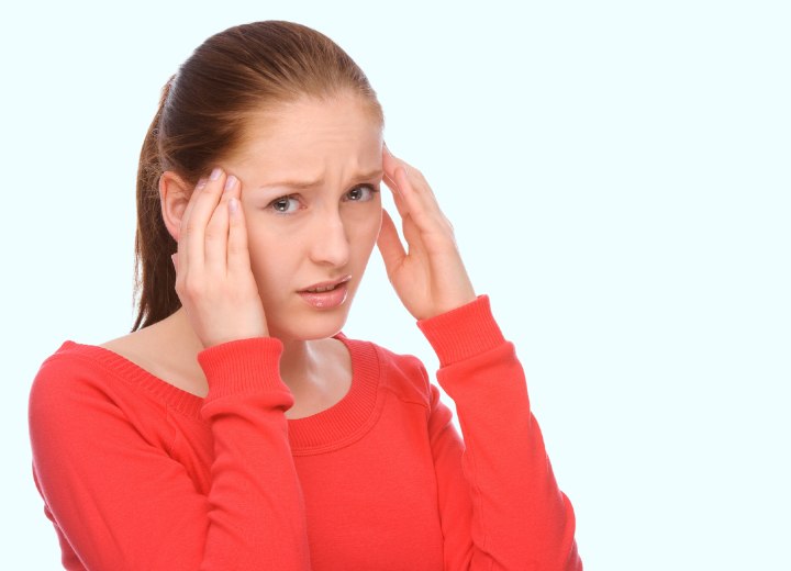 Woman with a ponytail sufering from a headache