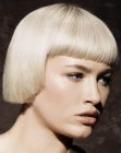 Sleek platinum blonde bob with bangs that cover half of the forehead