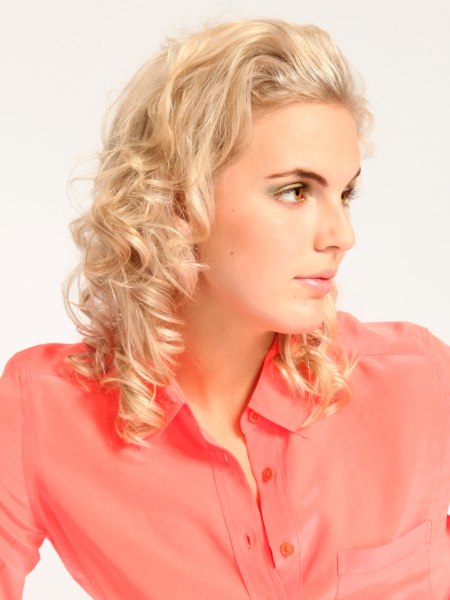 Romantic blonde hairstyle with spiraled curls and a silk blouse