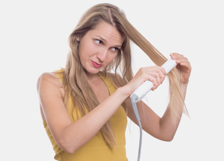 Woman who is styling her hair with a flat iron