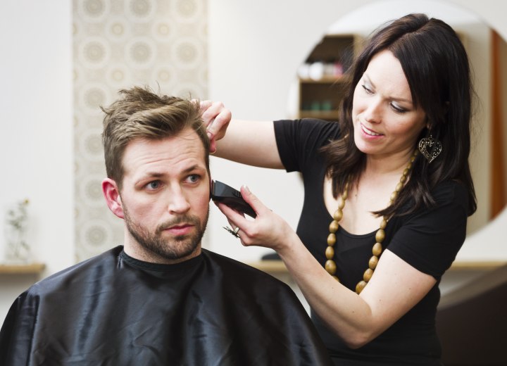 Female stylist cutting men's hair