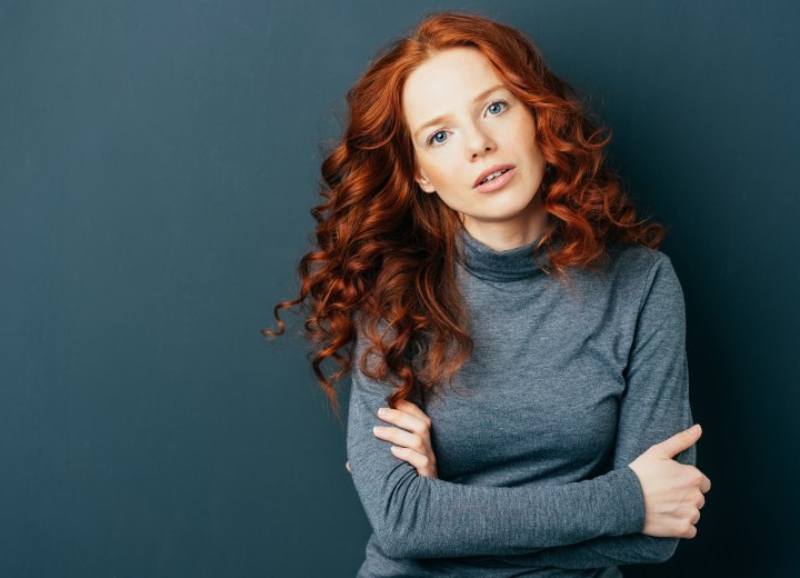 Long natural red hair with beautiful curls on a gray turtleneck top