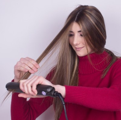 Girl flat ironing her long hair