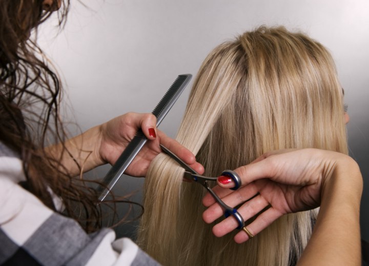 Hair stylist cuttting hair a woman's long hair off