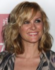 Bonnie Somerville with a curly hairstyle that touches her shoulders