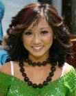 Brenda Song wearing her hair curled and feathered towards the back