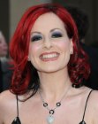 Carrie Grant wearing her red hair in a shoulder length style with curls