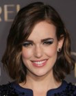 Elizabeth Henstridge with her brown hair cut in a below the chin bob with curls