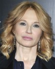 Ellen Barkin wearing a medium length hairstyle with long layers and spiral curls