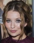 Emily Browning sporting an updo with a low bun and loose strands