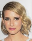 Emma Roberts sporting a medium length hairstyle with curls and a vintage appeal