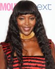 Naomi Campbell wearing her long black hair styled into small waves