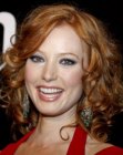 Redhead Alicia Witt wearing her layered hair long with shiny curls