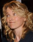 Lucy Lawless wearing her curly hair in a long style with side bangs