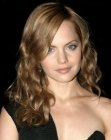 Mena Suvari with her long layered hair styled into curls and waves