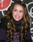 Miley Cyrus sporting a long hairstyle with a cascade of curls
