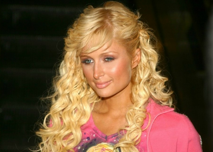 Paris Hilton with her long wavy hair styled behind one ear