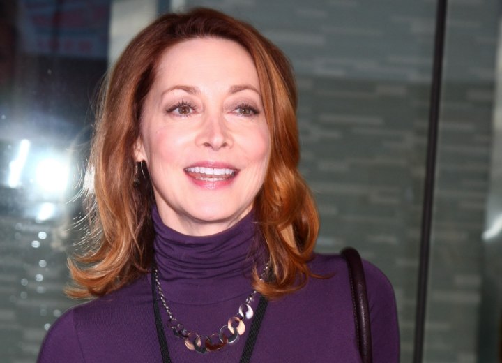 Sharon Lawrence wearing a purple turtleneck and past the shoulders hair