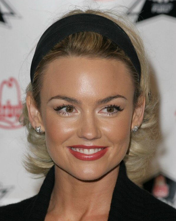 Kelly Carlson with her hair puffed up and wearing a headband