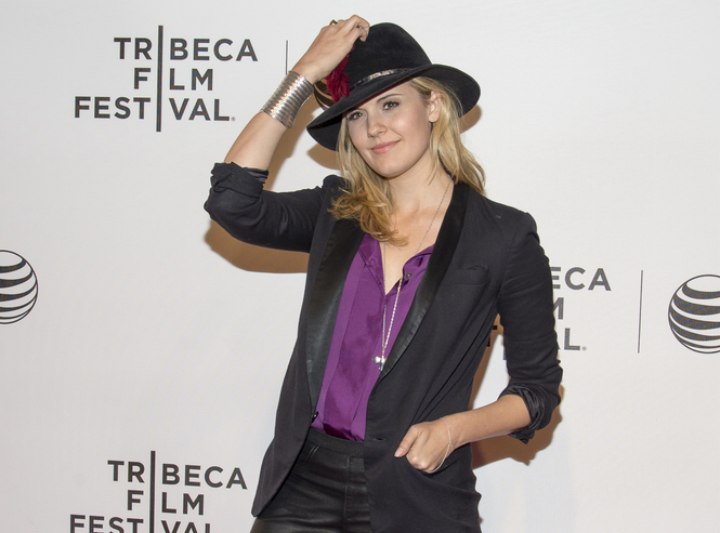 Maggie Grace wearing leather pants and a hat