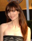 Saffron Burrows sporting a long hairstyle with bangs that fall over the eyes