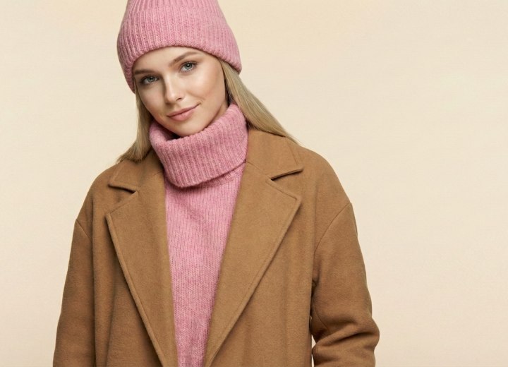 Frau mit langen blonden Haaren, Rollkragenpullover, Wintermantel und Mütze