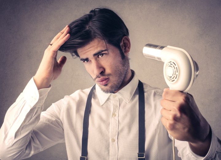 Ein Mann, der seine Haare föhnt