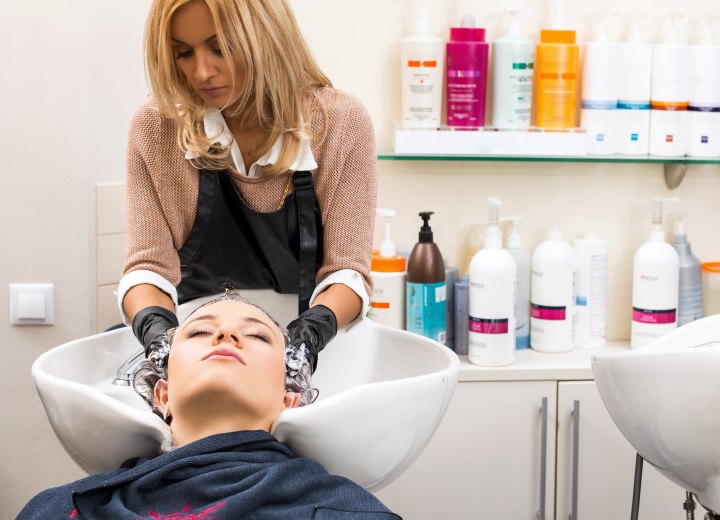 Coiffeuse lavant les cheveux d'un client dans un salon