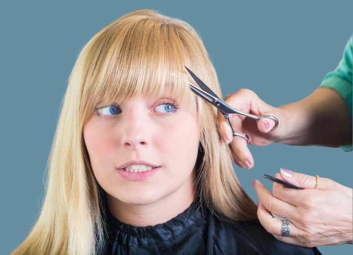 Coiffeur coupant la frange d'une cliente effrayée dans un salon de coiffure