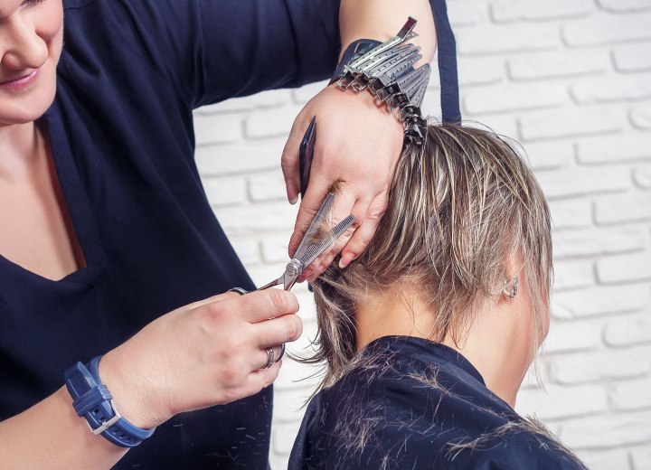 Femme portant une cape de salon de coiffure et se faisant couper les cheveux