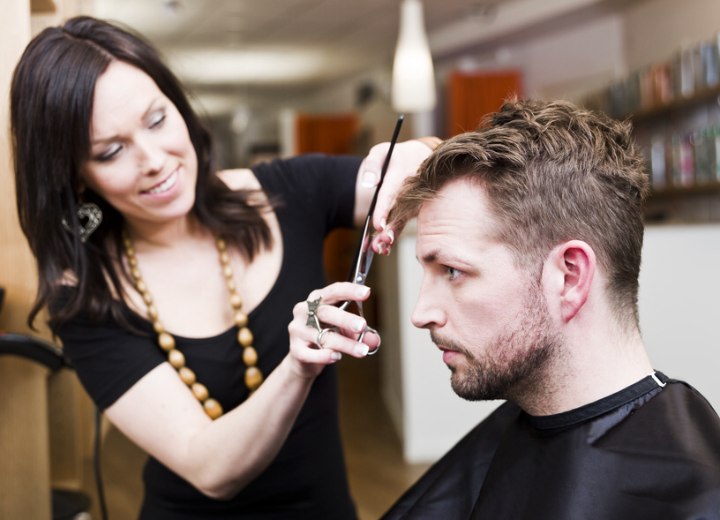 Coiffeuse qui coupe les cheveux d'un homme