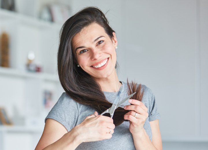 Femme qui coupe les pointes fourchues de ses propres cheveux