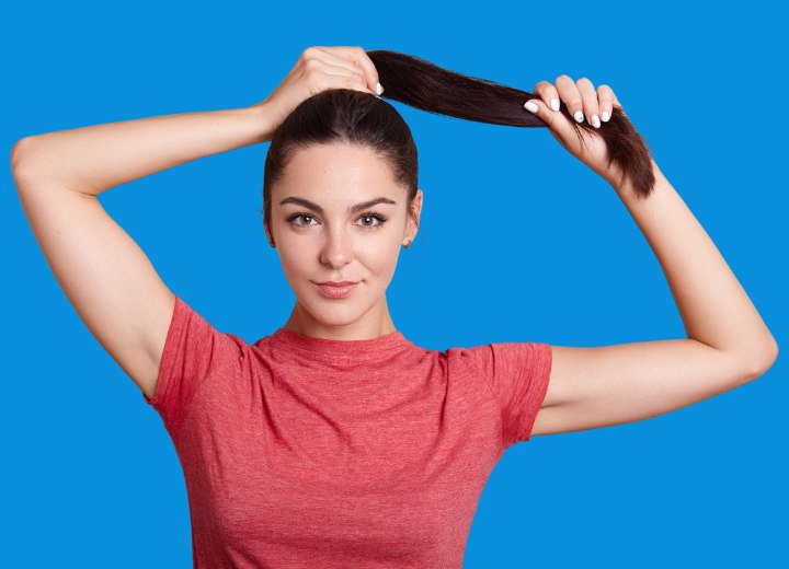 Femme qui attache ses cheveux en queue de cheval