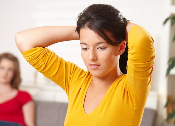 Young lady putting her hair up into a ponytail