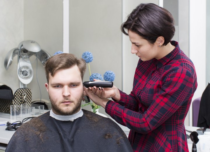 Man wearing a hair cutting cape when getting his hair cut with clippers