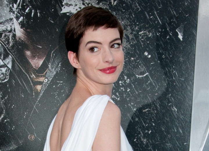 Anne Hathaway with short hair and wearing a white draped back dress