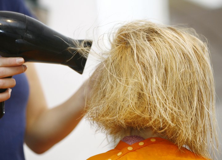 Hair stylist blow drying a layered haircut