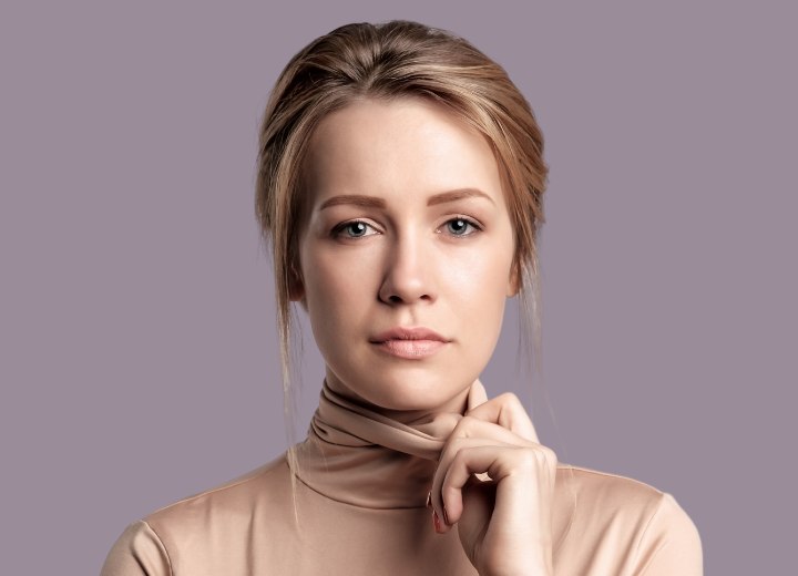 Woman wearing her hair in a loose bun and pulling her turtleneck