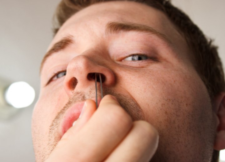 Man removing hair from inside his nose