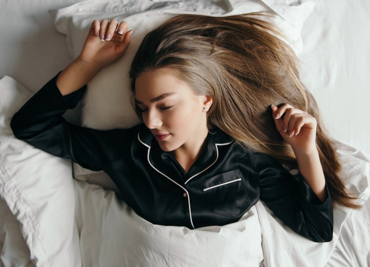 Sleeping girl with long straight hair wearing satin pajamas